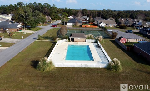 A swimming pool in a backyard with a tennis court and houses in the background.