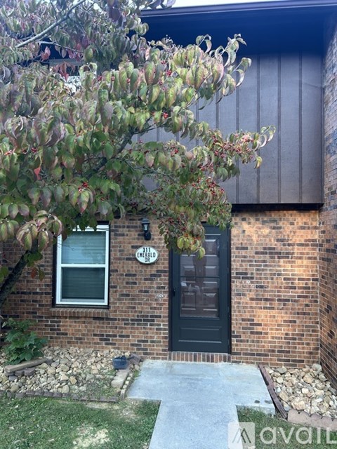 A house with a black door and a window is shown with a tree in front.