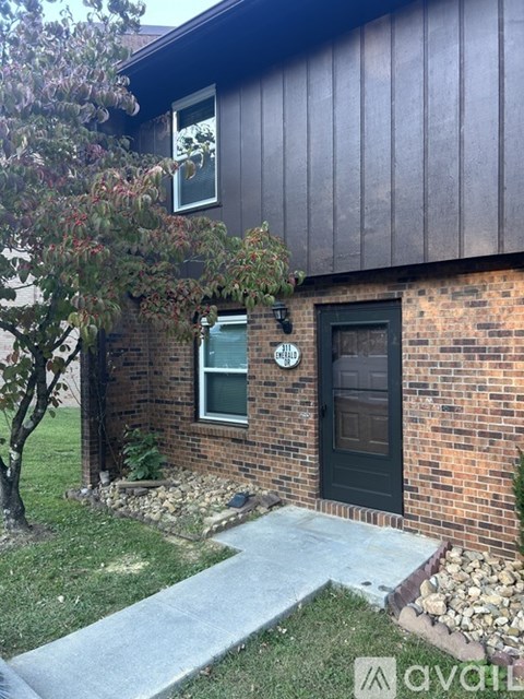 A house with a black door and a window with a tree in front.