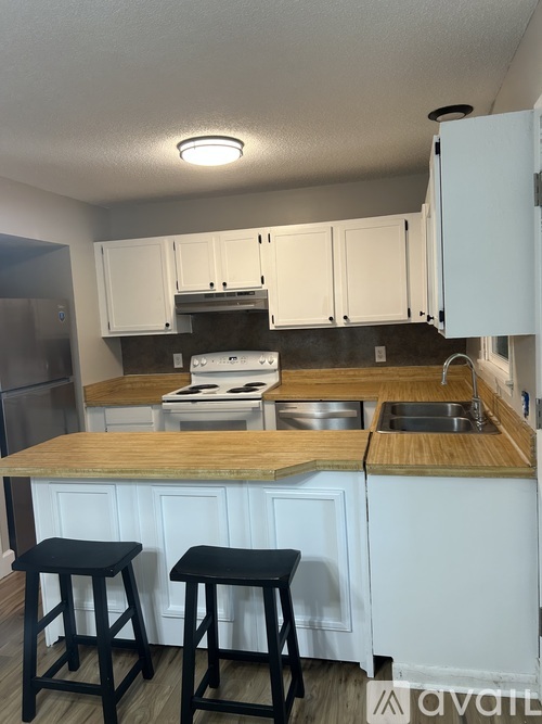 A kitchen with white cabinets and a wooden island.