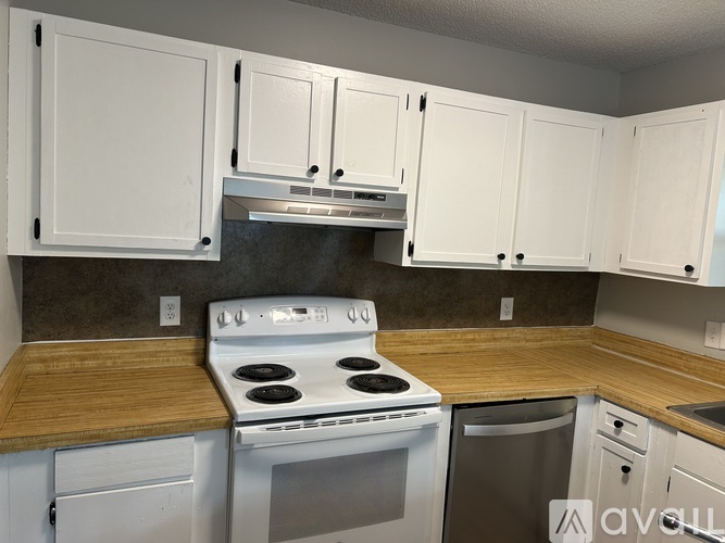 A kitchen with white cabinets and a stove top oven.
