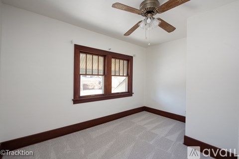 A room with a ceiling fan and a window with blinds.