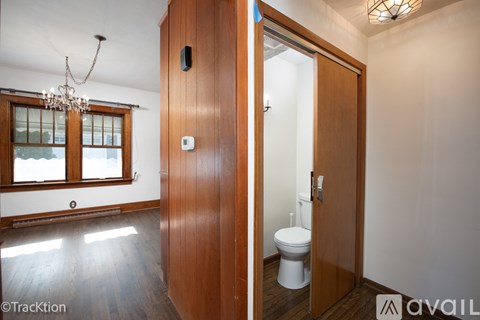 A wooden door with a white toilet in the bathroom.