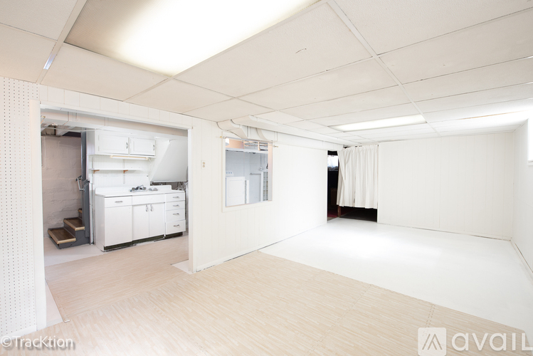 A large, empty room with a kitchen area in the background.