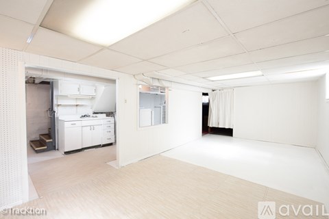 A large, empty room with a kitchen area in the background.