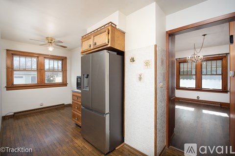 A kitchen with a refrigerator, wooden floors, and a ceiling fan.