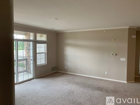 A spacious room with a carpeted floor and a sliding glass door leading outside.
