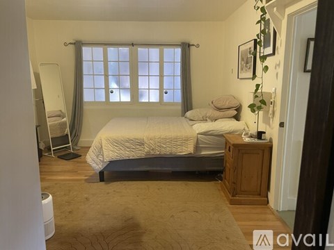 A bedroom with a large bed and a window with curtains.