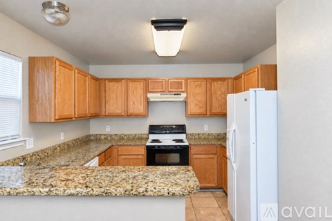 A kitchen with wooden cabinets and a granite countertop.