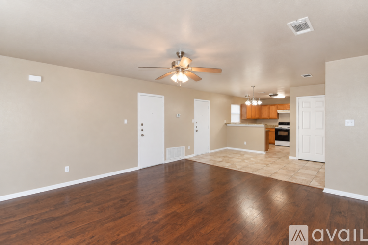 A spacious room with a ceiling fan and wooden flooring.