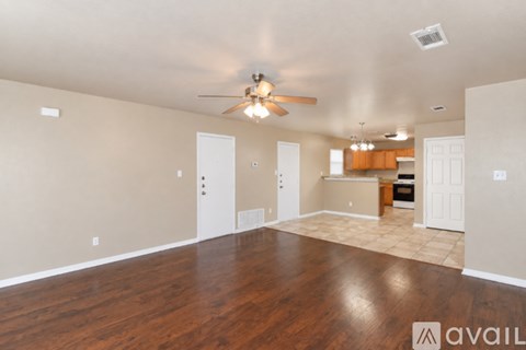 A spacious room with a ceiling fan and wooden flooring.