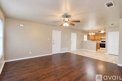 A spacious room with a ceiling fan and wooden flooring.