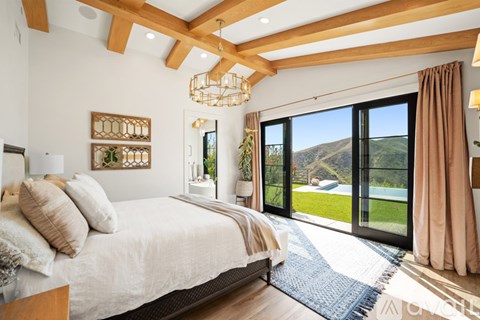 A bedroom with a large bed and a view of the outdoors through the sliding glass doors.