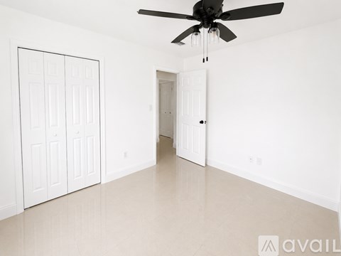 A room with a ceiling fan and two doors.