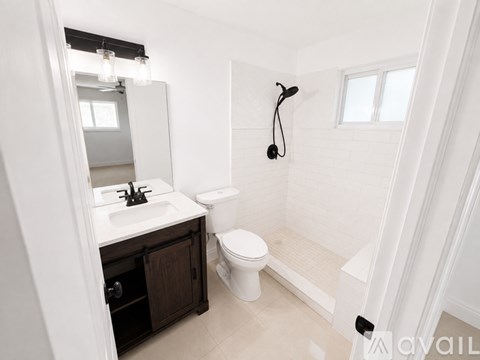 A white bathroom with a toilet, sink, and a mirror.