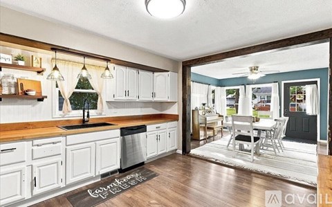 A kitchen with white cabinets and a black mat on the floor.