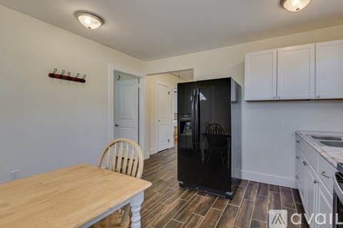A kitchen with a wooden table and a black refrigerator.