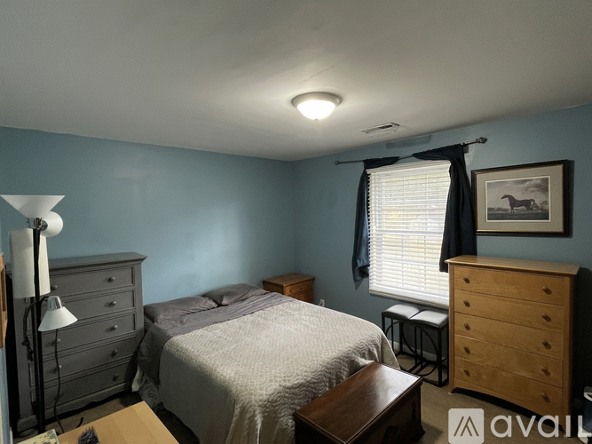 A bedroom with a bed, nightstand, and a painting on the wall.