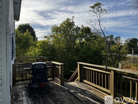 A deck with a chair and a table is surrounded by trees.