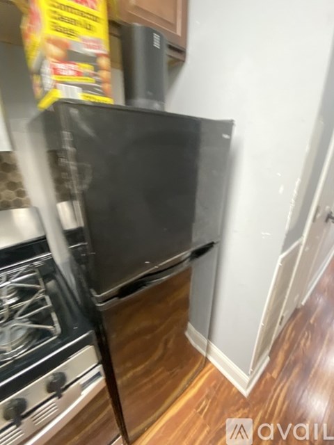 A black refrigerator is tilted to one side in a kitchen.