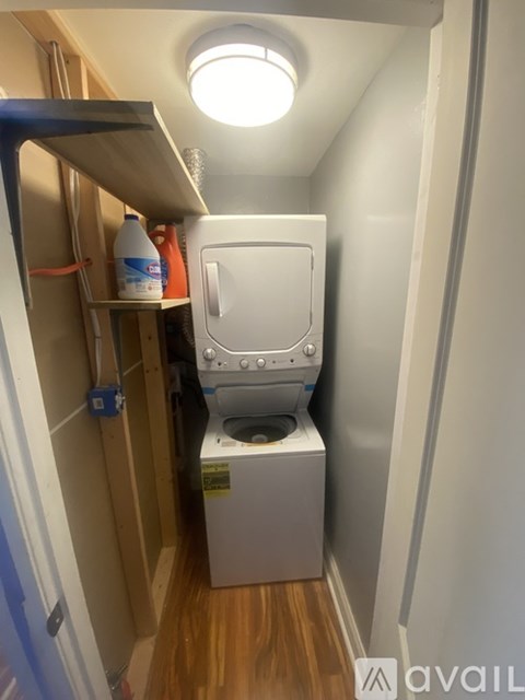 A small white toilet is in a narrow space under a cabinet.