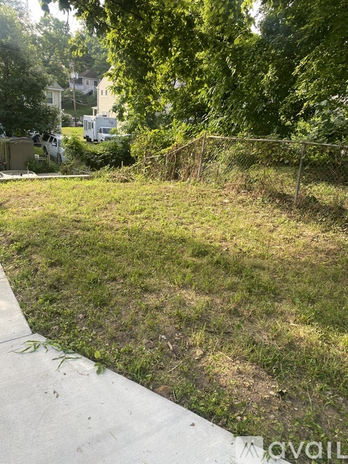 A grassy area with a fence and trees in the background.