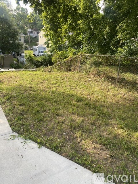 A grassy area with a fence and trees in the background.