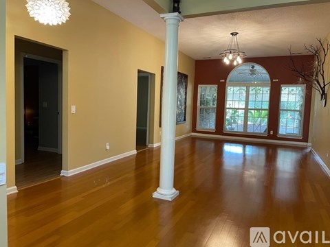 A spacious room with wooden floors and a large window.