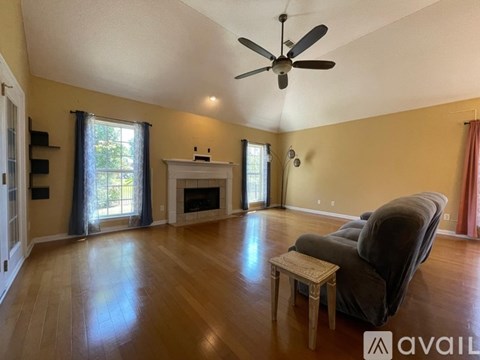 A living room with a grey couch, a fireplace, and a ceiling fan.