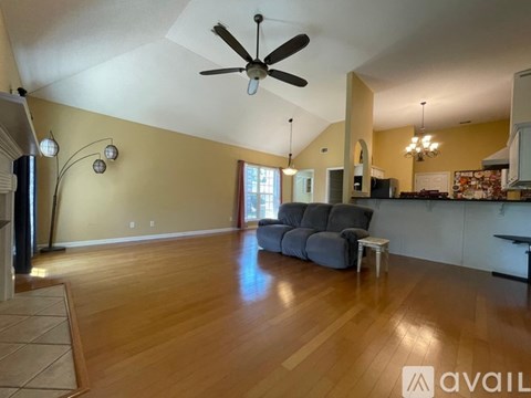 A spacious living room with a grey sofa and a ceiling fan.