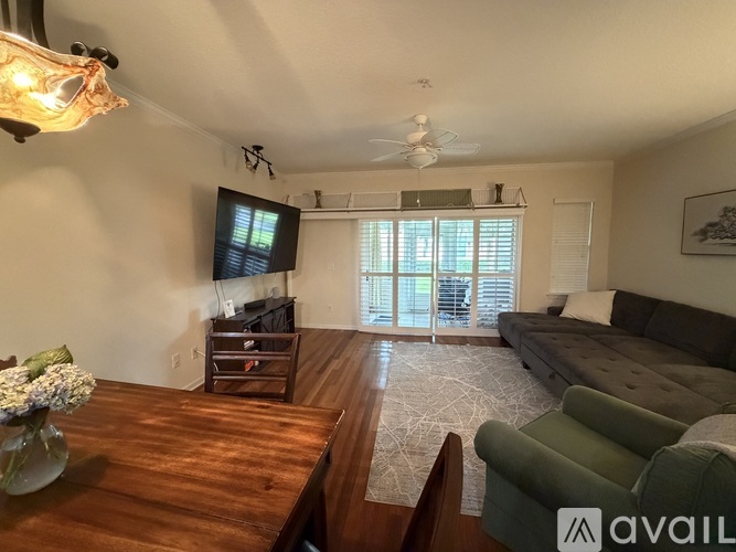 A living room with a dark wood floor and a grey couch.