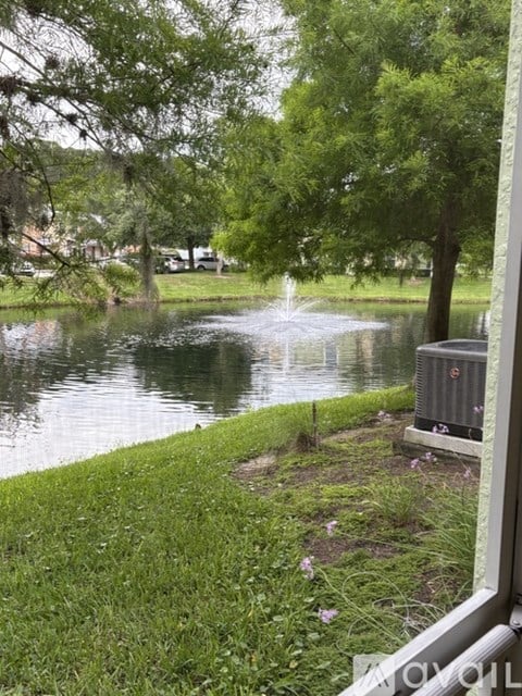 A fountain in the middle of a pond surrounded by green grass.