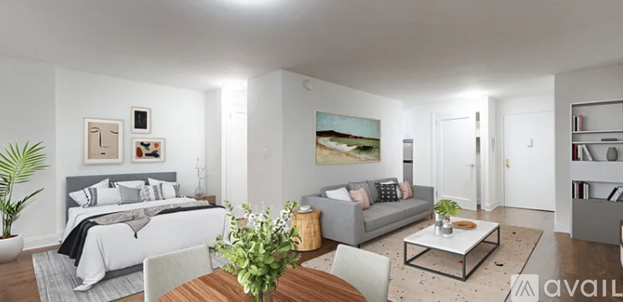 A well-lit, modern living room with a grey couch, a white bed, and a coffee table.