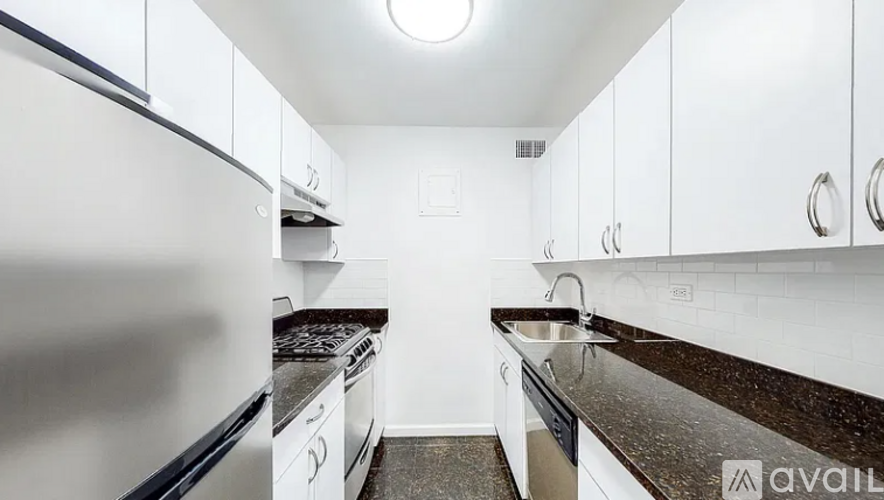 A kitchen with white cabinets and a stainless steel refrigerator.