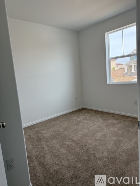 A room with a carpeted floor and a window showing a building outside.