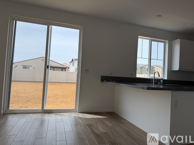 A kitchen with a large window and a view of a backyard.