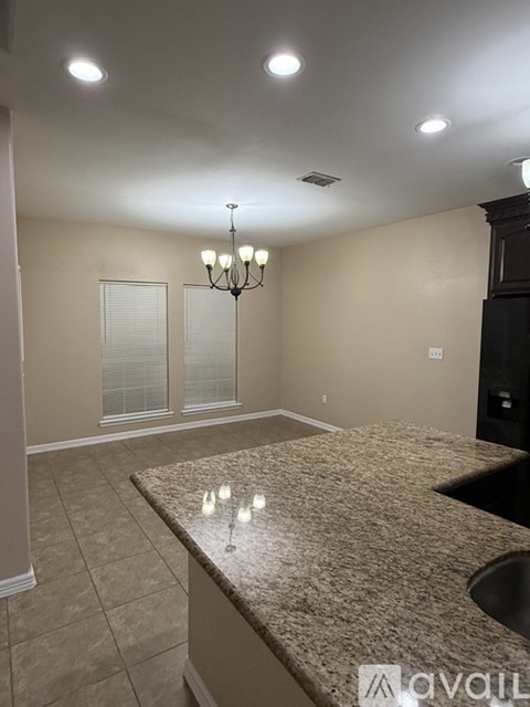 A kitchen with granite countertops and a chandelier.