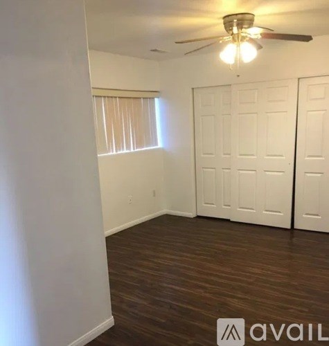 A room with a ceiling fan and wooden flooring.