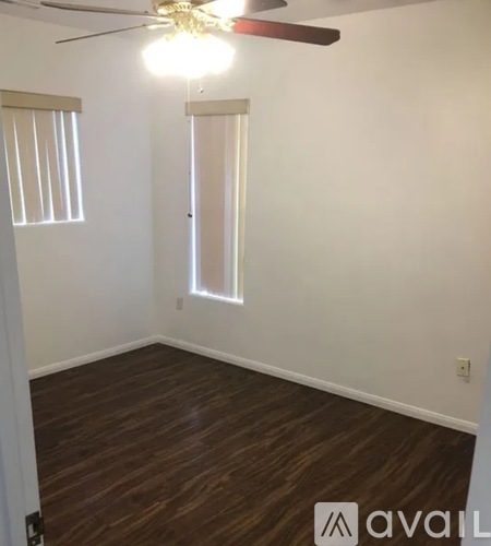 A room with a ceiling fan and wooden flooring.