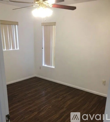 A room with a ceiling fan and wooden flooring.