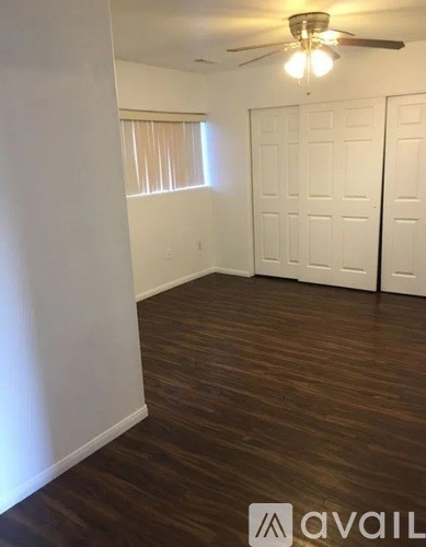 A room with a ceiling fan and wooden flooring.