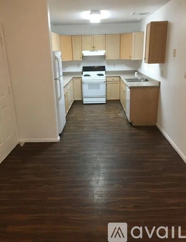 A kitchen with white appliances and wooden cabinets.
