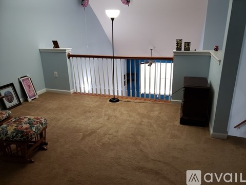 A living room with a carpeted floor and a staircase with a railing.
