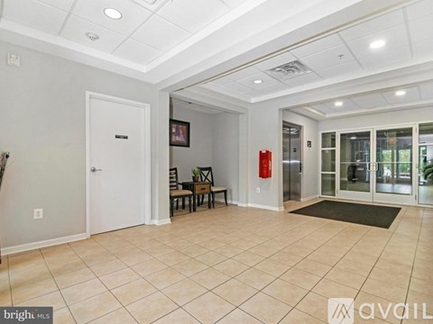 A spacious room with a white door, a fire extinguisher, and a glass door leading to another room.