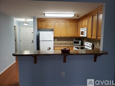 A kitchen with a white refrigerator and wooden cabinets.