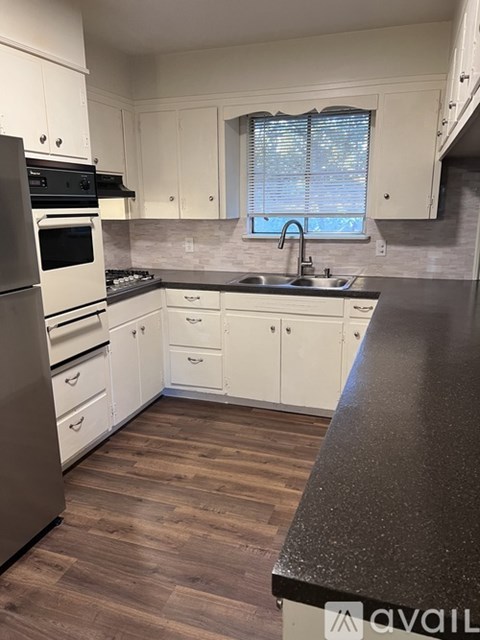 A kitchen with white cabinets and a black countertop.