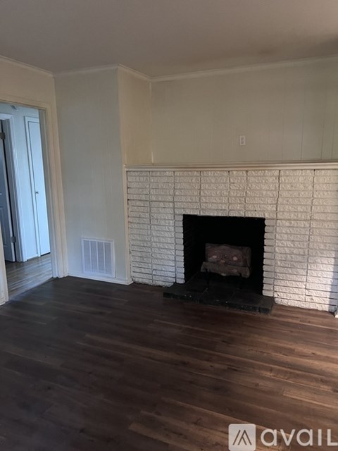 A white brick fireplace in a room with wooden floors.