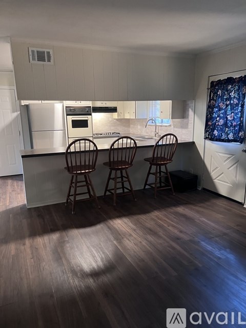 A kitchen with white cabinets and a wooden floor.