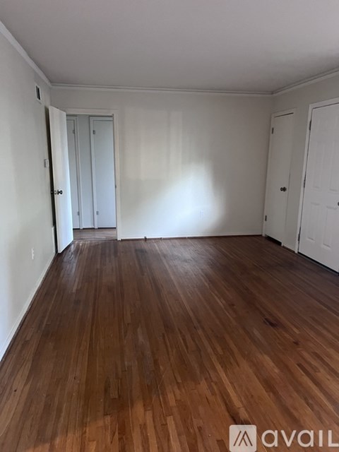 A room with wooden flooring and white walls.