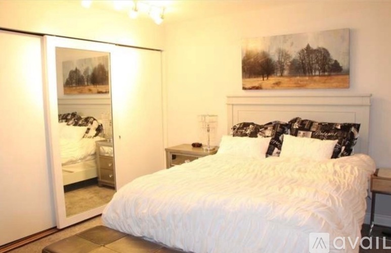 A bedroom with a large bed and a painting on the wall.
